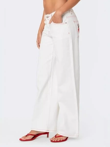 White wide-leg denim jeans with red contrast stitching and embroidery details