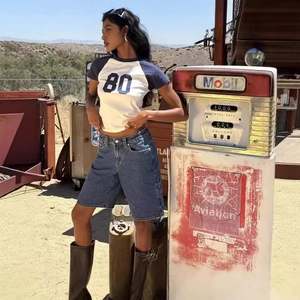 Scatto all'aperto di pantaloncini di jeans larghi con t-shirt rétro anni '80 e stivali neri