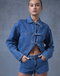 Détail d'une veste en jean bleu foncé avec des nœuds élégants et un short assorti