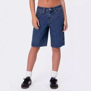 Dettaglio del tessuto denim blu scuro e delle cuciture su questi pantaloncini larghi