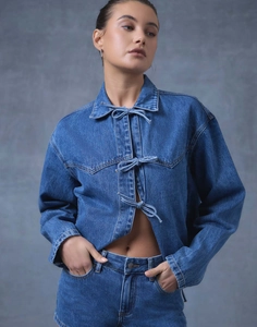 Détail d'une veste en jean ample avec trois nœuds papillon et une finition en coton