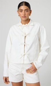 Détail d'une veste en jean blanc crème avec quatre nœuds et texture de tissu visible