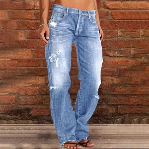 Detail view of distressed light blue denim jeans with ripped knees and vintage wash effects