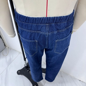 Detail view of denim jeans featuring elastic waistband and rear pockets with yellow stitching