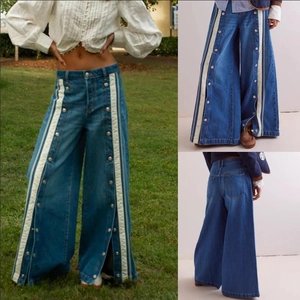Detail of vintage blue wide-leg jeans with white side stripes and silver snap buttons
