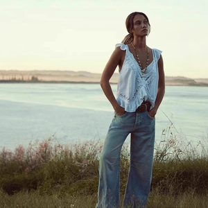 Détail d'un haut blanc sans manches à col en V et d'un pantalon en jean bleu clair large