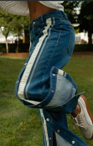 Macro shot of high-waist flared jeans with white side stripes and metal snap button details