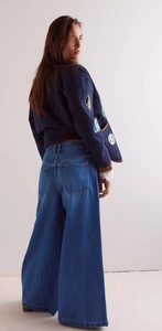 Detail of high-waist wide-leg jeans with embroidered badge denim jacket on a model