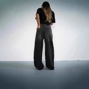 Detail of vintage wide-leg denim jeans with gradient wash effect and V-stitch back pocket