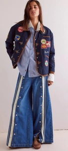 Detail of wide-leg jeans with white side stripes and metal snap buttons decoration