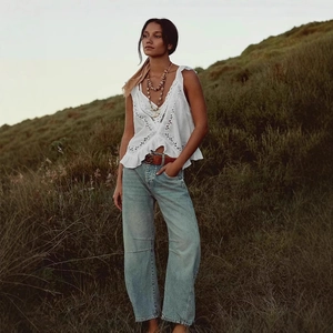 Détail d'un jean bleu clair à taille haute et jambe large avec ceinture vintage en cuir