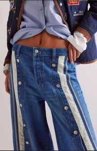 Detail of wide-leg jeans with side metal button accents and contrast cream panels