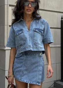 Detail of blue denim two-piece set featuring short sleeve top with large flap pockets