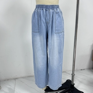 Detail view of high waist light blue wide leg denim pants with elastic waistband and pockets