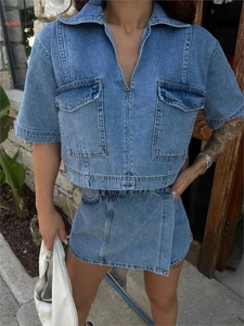 Detail of blue wash denim two-piece set featuring short jacket with large utility pockets
