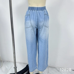 Detail of light blue washed denim pants with elastic waist and large square pockets