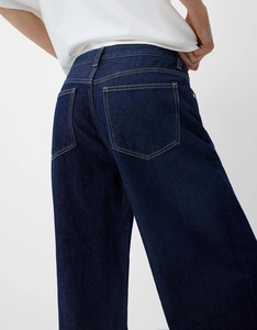 Vue détaillée des poches arrière sur un jean en denim bleu foncé avec surpiqûres contrastées