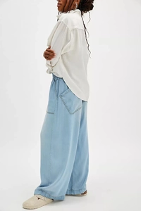 Detail view of light blue wide leg denim trousers with elastic high waist and large pockets