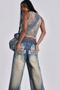 Détail du jean délavé vintage avec grand imprimé aile et ornements en rivets métalliques