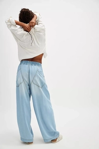 Back view of light blue wide-leg denim pants featuring elastic waist and large rear pockets