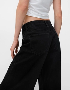 Détail des poches arrière et de la coupe de ce jean noir délavé à jambes larges pour femme