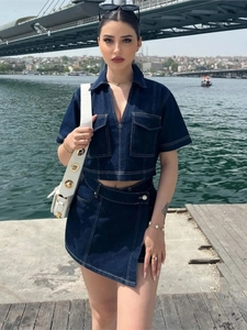 Detail of dark blue denim two-piece set with white contrast stitching and asymmetric skirt