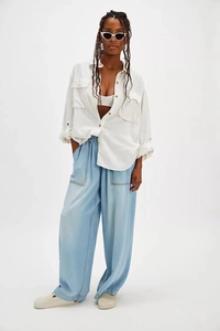 Detail of light blue wide-leg denim trousers with elastic high waist and large patch pockets