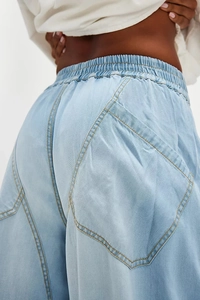 Detail view of light blue denim pants featuring contrast stitching and large geometric pockets