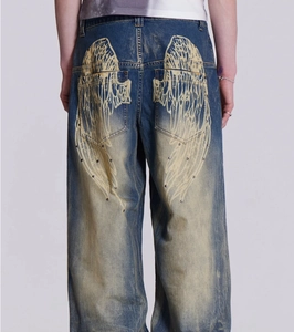 Vue détaillée du jean bleu clair à jambes larges avec imprimé ailes et clous métalliques