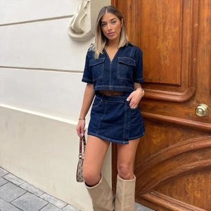 Detail of dark blue denim two-piece set featuring contrast stitching and cargo pockets