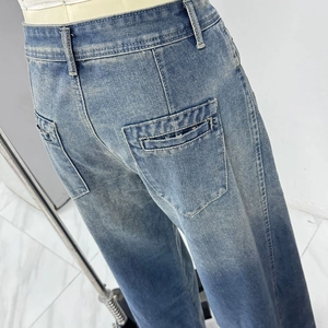 Dettaglio dei jeans a vita alta con sfumatura blu, tasche posteriori ed bordi sfrangiati