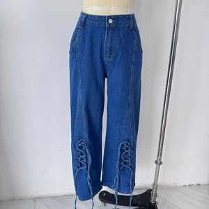Détail de ce jean en denim bleu avec un design unique à lacets et ajouré sur le bas