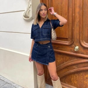 Detail of dark blue denim two-piece set featuring contrast stitching and asymmetric mini skirt