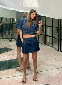 Detail of dark blue denim two-piece set with white contrast stitching and asymmetric waist