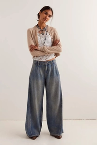 Dettaglio dei jeans a vita alta a gamba larga con lavaggio vintage blu e pieghe frontali