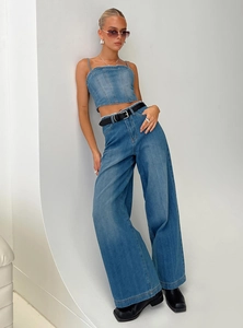 Détail d'un ensemble en jean bleu délavé avec haut court et jean large à taille haute