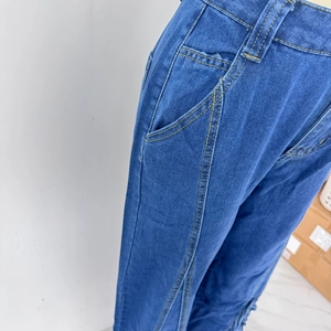 Détail du pantalon en jean bleu avec surpiqûres jaunes et poches latérales à la taille