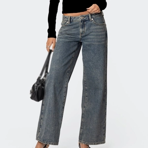Nahaufnahme der Hüftjeans mit weitem Bein, Metallknopf und gewaschener Textur in Blau