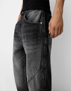 Detailed view of dark grey washed denim trousers with heavy stitching and cargo pockets