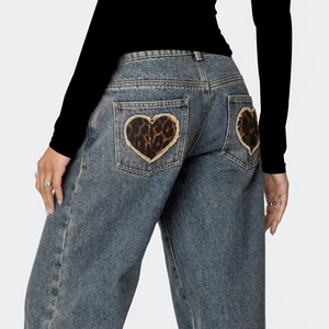 Detail von Herz-Patches mit Leopardenmuster auf den Gesäßtaschen der blauen Jeanshose