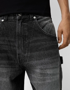 Close-up of stone-washed dark grey denim jeans showing metal rivets and pocket stitching