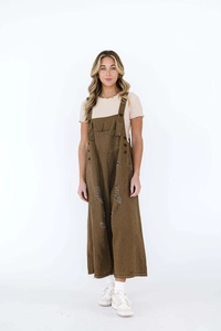 Detail of distressed olive green denim dungarees with metal buttons and large front pocket