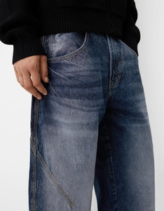 Detail of men's slim retro denim jeans showing dark blue wash and whiskering craft