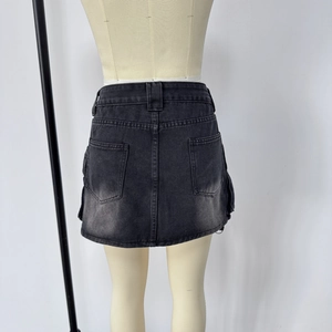 Détail d'une mini-jupe en jean noir délavé avec poches cargo et surpiqûres visibles