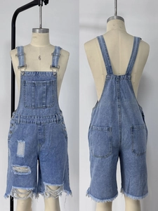 Détails d'un short salopette en jean bleu clair avec déchirures et finitions bords francs