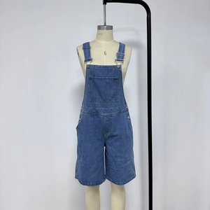 Detail of blue denim overall shorts featuring adjustable metal buckles and chest pocket