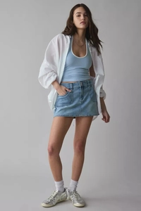 Minifalda vaquera elegante de talle alto con cárdigan blanco y zapatillas plateadas