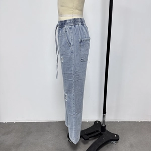 Detail view of light blue ripped denim jeans with elastic drawstring waist on mannequin