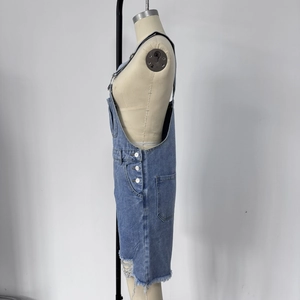 Détail de la salopette courte en jean bleu clair avec boutons et ourlet effiloché