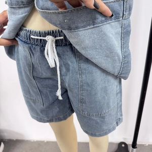 Dettaglio degli shorts in denim a vita alta con coulisse bianca ed elastico nel completo blu